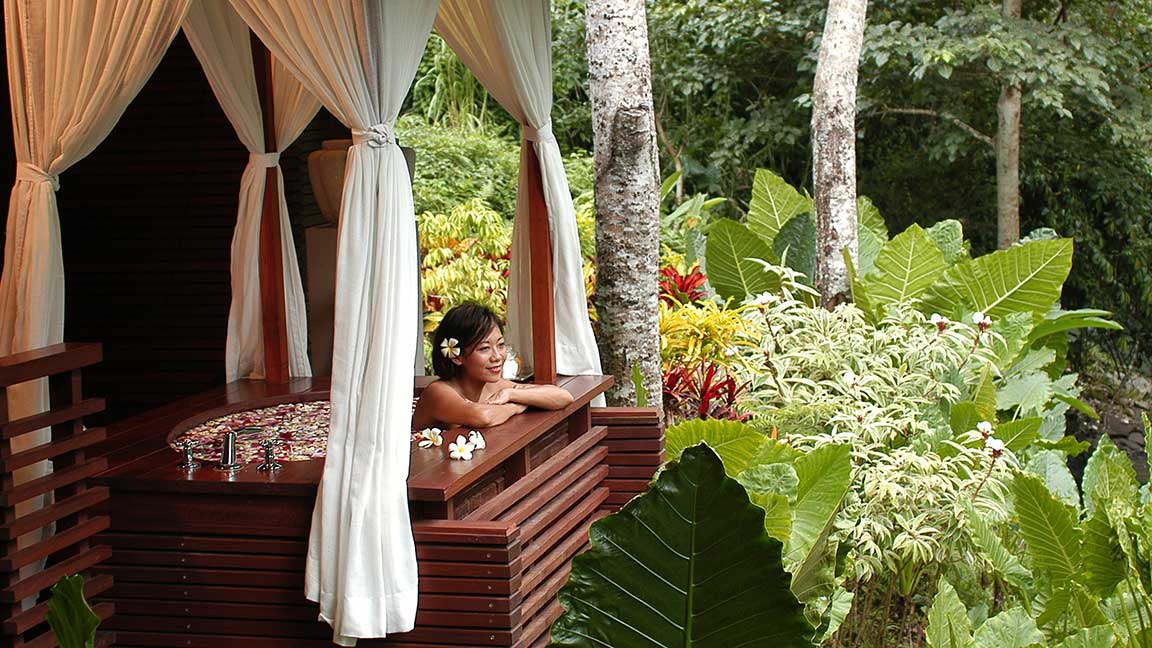 Frau entspannt in Jacuzzi mit Blick in das grüne Blätterdach im Maya Ubud Resort & Spa auf Bali