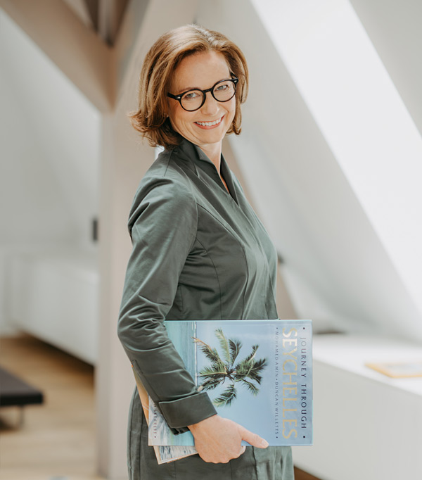 Reise-Expertin Katharina Fenners mit Prospekten unterm Arm - auf der Suche nach engagierten neuen Mitarbeitern, die ihren Beruf lieben! Bewerben Sie sich jetzt und machen Sie Karriere bei Fenners Reisen!