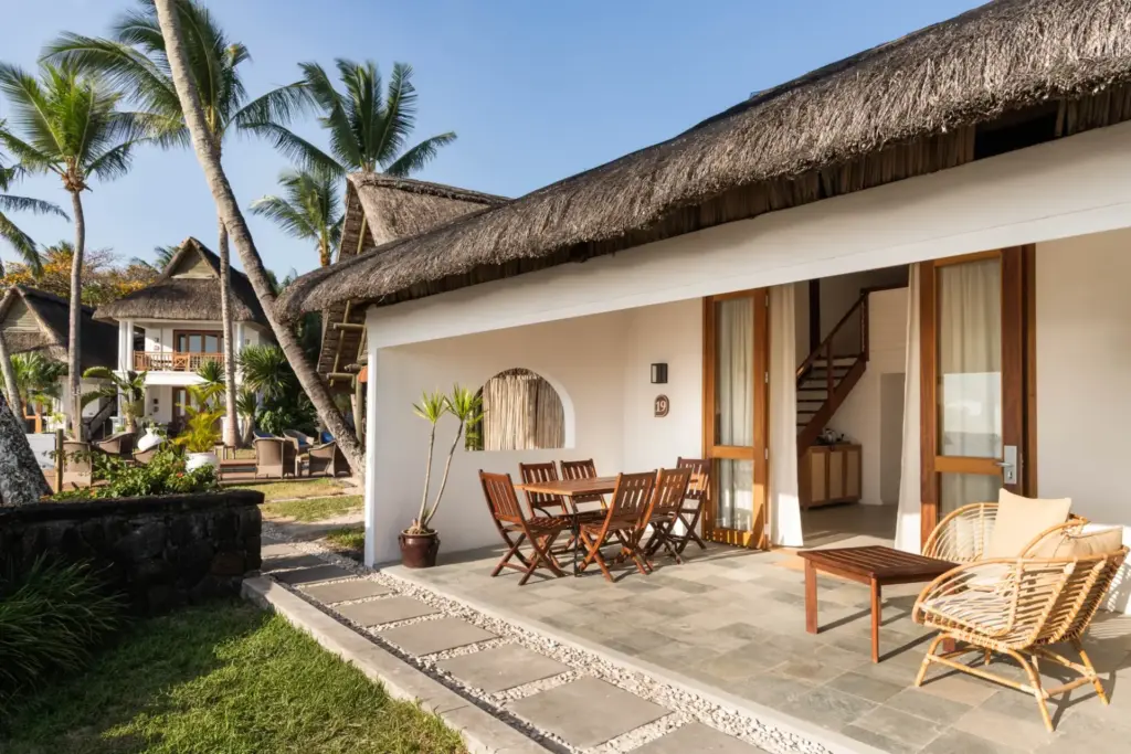 Gemütliche Terrasse mit Korbsesseln und Essecke vor einer palmgedeckten Unterkunft des Constance Sakoa Boutik Hotels, im Hintergrund Palmen