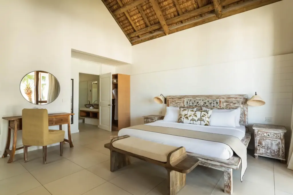 Elegantes und helles Schlafzimmer des Constance Sakoa Boutik auf Mauritius - unter hoher Holzdecke, mit Schreibtisch und angegliedertem Bad
