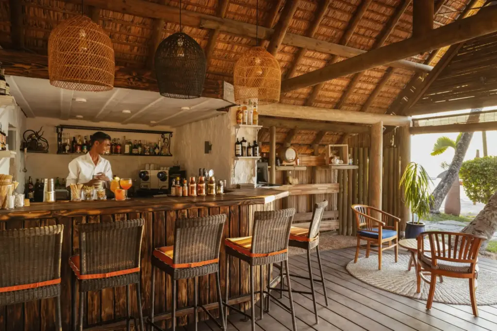 Bartresen mit Barhockern und Sitzgelegenheiten unter hohen Decken - hier wartet köstliche Erfrischung in authentischem Ambiente! Buchen Sie Ihren nächsten Mauritius Urlaub bei Fenners Reisen!