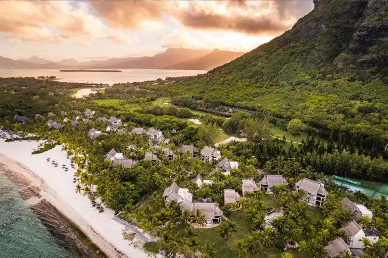 Blick aus der Luft auf die spektakuläre Anlage des Dinarobin Beachcomber Golf Resort & Spa am Fuße des Le Morne Brabant, während im Hintergrund die Sonne untergeht - Katharina Fenners verwirklicht unvergessliche Tage auf der Trauminsel Mauritius!