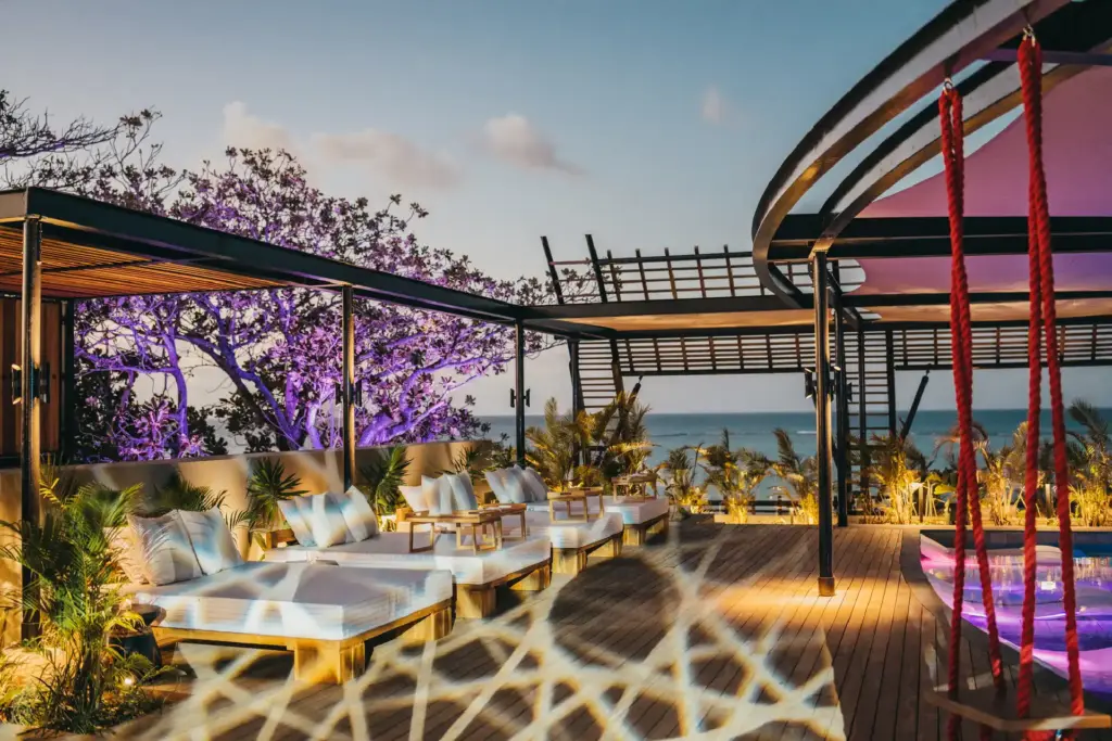 Liegen, lila Vegetation und der Ozean im Hintergrund - das LUX Grand Baie auf Mauritius, buchbar bei Fenners Reisen