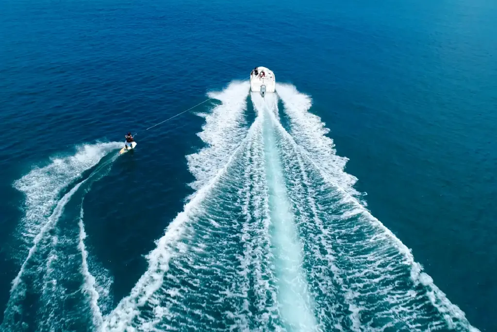 Ein Speedboot zieht einen auf einem Sportbrett stehenden Mann durch den tiefblauen Ozean - Mauritius ist ein Paradies für Liebhaber des Wassersports. Fenners Reisen organisiert Ihren intimen Luxusurlaub im Paradies.