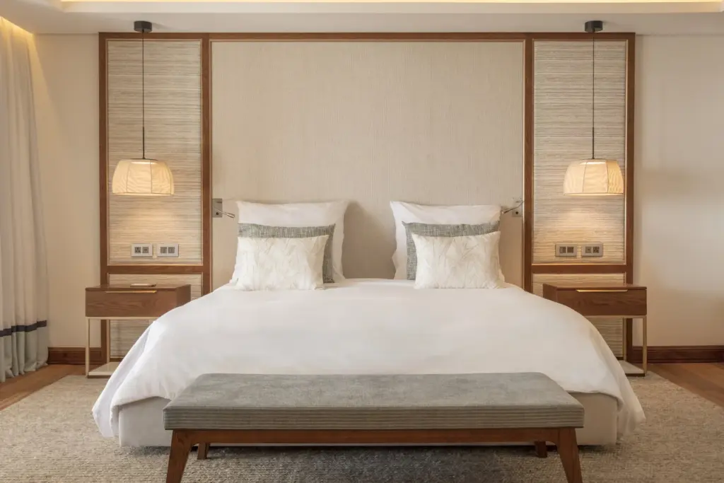 Ein weißes Hotelbett, umrahmt von schickem Dekor - die Ausstattung des Paradis Beachcomber Golf Resort & Spa lässt keine Wünsche offen. Buchbar ist der Aufenthalt bei Fenners Reisen.