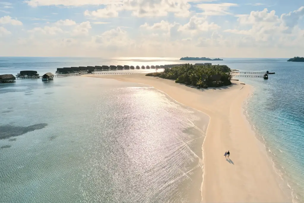 Ein Paar spaziert über eine endlose Sandbank, die zwei Insen auf den Malediven miteinander verbindet. Buchen Sie eine unvergessliche Insel-Auszeit bei Fenners Reisen!