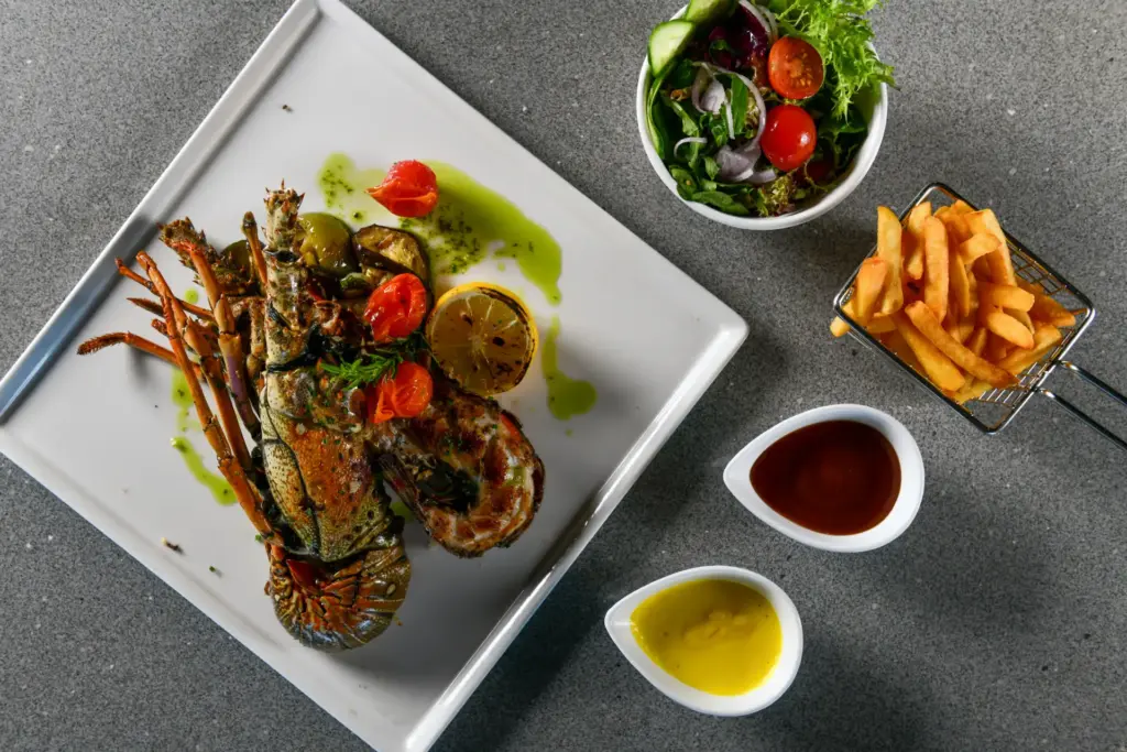 Hummer mit Beilagen, kunstvoll arrangiert - auf den Malediven lässt es sich vorzüglich speisen, viele Hotels punkten mit ausgezeichneter Kulinarik. Katharina Fenners kennt sich auf den Malediven persönlich aus und berät Sie individuell!