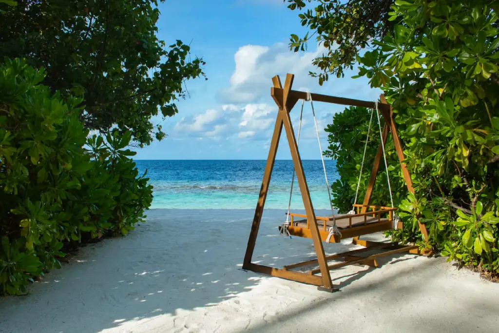 Eine Schaukel an einem idyllischen Sandstrand mit Blick auf den türkisen Indischen Ozean - Katharina Fenners ist Expertin für Luxusreisen auf die Malediven und berät Sie individuell!