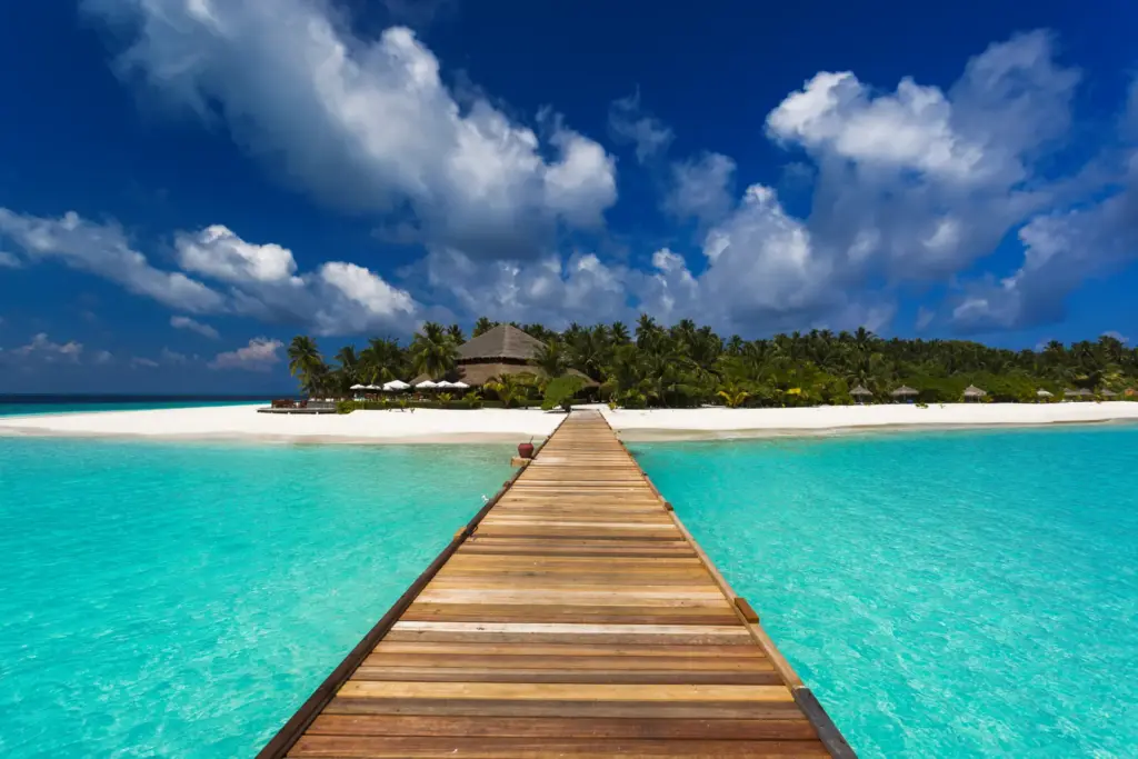 Ein Steg führt über den türkisen Indischen Ozean zur unberührten Insel Filitheyo und dem gleichnamigen Filitheyo Island Resort, buchbar bei Fenners Reisen