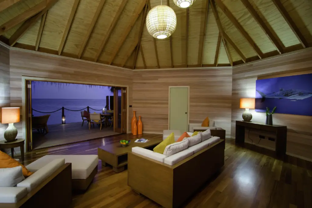 Der Wohnbereich einer Wasser-Villa bei Nacht. Buchen Sie einen unvergesslichen Luxusurlaub auf den Malediven bei der Trauminsel-Expertin Katharina Fenners!