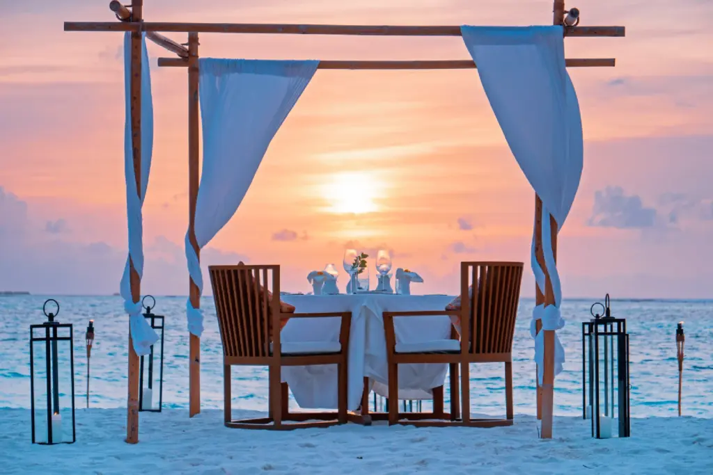 Ein romantisch gedeckter Tisch für zwei am Strand, während die Sonne orange in den Ozean taucht - die Malediven sind das ideale Ziel für Hochzeiten und Flitterwochen. Katharina Fenners berät Sie individuell und designt einen unvergesslichen Aufenthalt!