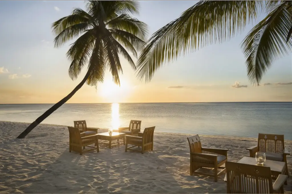 Eine Sitzgruppe im Sonnenuntergang, davor Palmen - verbringen Sie einen romantischen Urlaub auf Mauritius. Katharina Fenners arrangiert auch Hochzeitsreisen und Flitterwochen im Indischen Ozean!