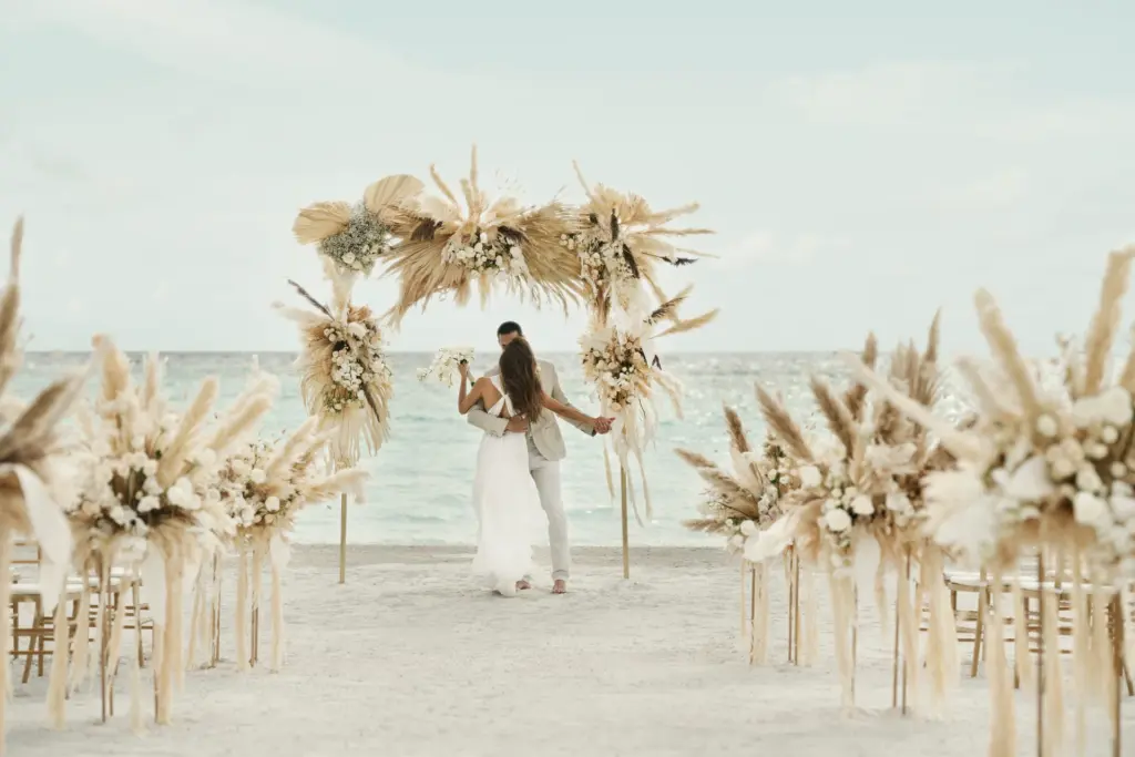 Ein Paar gibt sich am maledivischen Strand das Ja-Wort. Auch Hochzeiten und Flitterwochen auf den Malediven können bei Fenners Reisen gebucht werden!