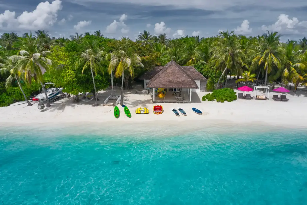 Bunte Boote liegen auf dem strahlend weißen Sandstrand vor dem Seaside Finolhu Baa Atoll Maldives, buchbar bei Fenners Reisen