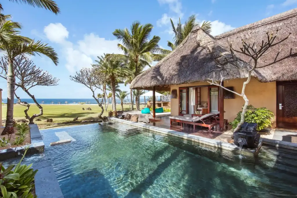 Eine palmgedeckte Villa mit schimmerndem Pool und Blick auf den Ozean - buchen Sie einen Aufenthalt in einer exklusiven Villa auf Mauritius, Katharina Fenners berät Sie persönlich!