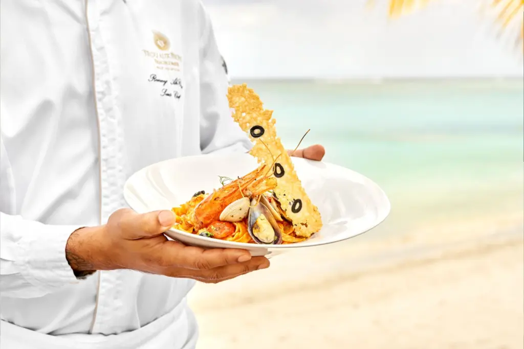 Ein Kellner serviert Hummer direkt am Strand - die Inseln im Indischen Ozean haben auch kulinarisch einiges zu bieten. Katharina Fenners kennt sich bestens aus und plant Ihren Traumurlaub!