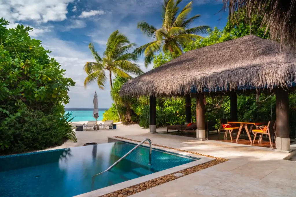 Blick auf den stilvollen Außenbereich einer Strandvilla mit Meerblick, eigenem Pool und einem beschatteten Pavillon - Sie sind auf der Suche nach der perfekten Luxusvilla für Ihren Maledivenurlaub? Katharina Fenners kennt die besten Villen und Resorts und berät Sie individuell!