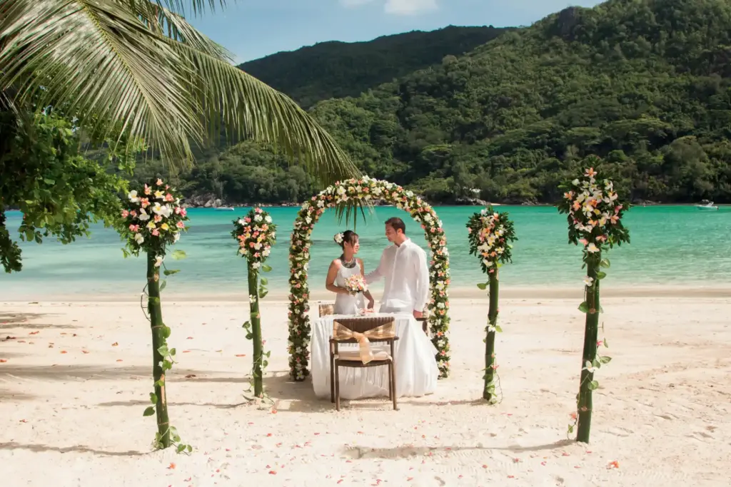 Ein Paar heiratet an einem Bilderbuchstrand auf den Seychellen. Sie planen eine Hochzeit oder Flitterwochen auf einer der Trauminseln des Indischen Ozeans? Trauminsel-Spezialistin Katharina Fenners macht es möglich!