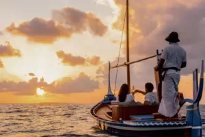 Romantik pur: Ein Paar segelt auf einem traditionellen Dhoni in den lodernden Sonnenuntergang. Buchen Sie Ihre Hochzeit auf den Malediven bei Fenners Reisen! Die Malediven sind auch für Flitterwochen, Erneuerungen des Eheversprechens oder eine romantische Auszeit als Paar ein hervorragendes Ziel.