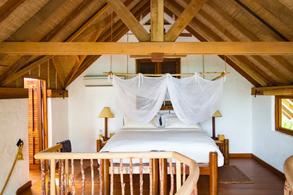 Das Schlafzimmer dieser Crusoe Suite mit Pool im Soneva Fushi Resort auf den Malediven liegt urig auf der zweiten Etage. Buchbar ist der Aufenthalt bei Fenners Reisen.