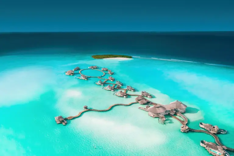 Blick aus der Luft auf den unfassbar türkisen Ozean, gesprenkelt mit weißen Sandbänken - das ist die paradiesische Kulisse des Soneva Jani auf den Malediven, buchbar für Ihren Malediven Luxusurlaub bei Fenners Reisen