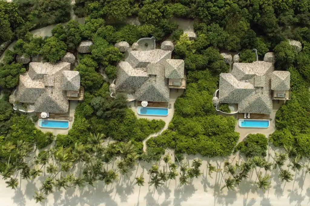 Blick aus der Vogelperspektive auf drei imposante Beachvillen mit privatem Pool direkt am weißen Bilderbuchstrand einer einsamen Insel und umschlungen von üppiger tropischer Vegetation - Katharina Fenners kennt die exklusivsten Resorts im Indischen Ozean und berät Sie individuell!