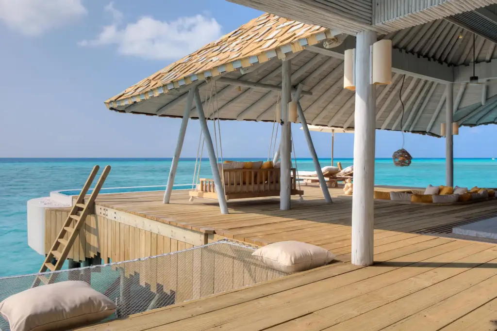 Die großzügige Terrasse dieses Overwater Hideaways punktet mit eigener Schaukel und einer Leiter, die direkt hinab ins Meer führt - buchbar für Ihren Malediven Urlaub bei Fenners Reisen