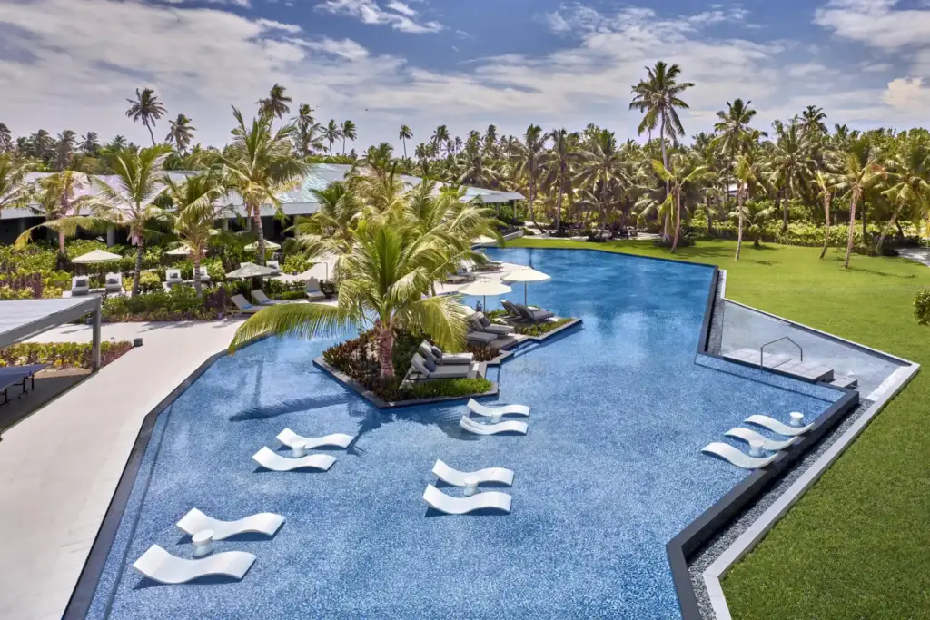 Blick auf den traumhaften Hauptpool des stilvollen Waldorf Astoria Seychelles auf der nahezu unberührten Platte Island - buchbar für Ihren Luxusurlaub auf den Seychellen bei Fenners Reisen!