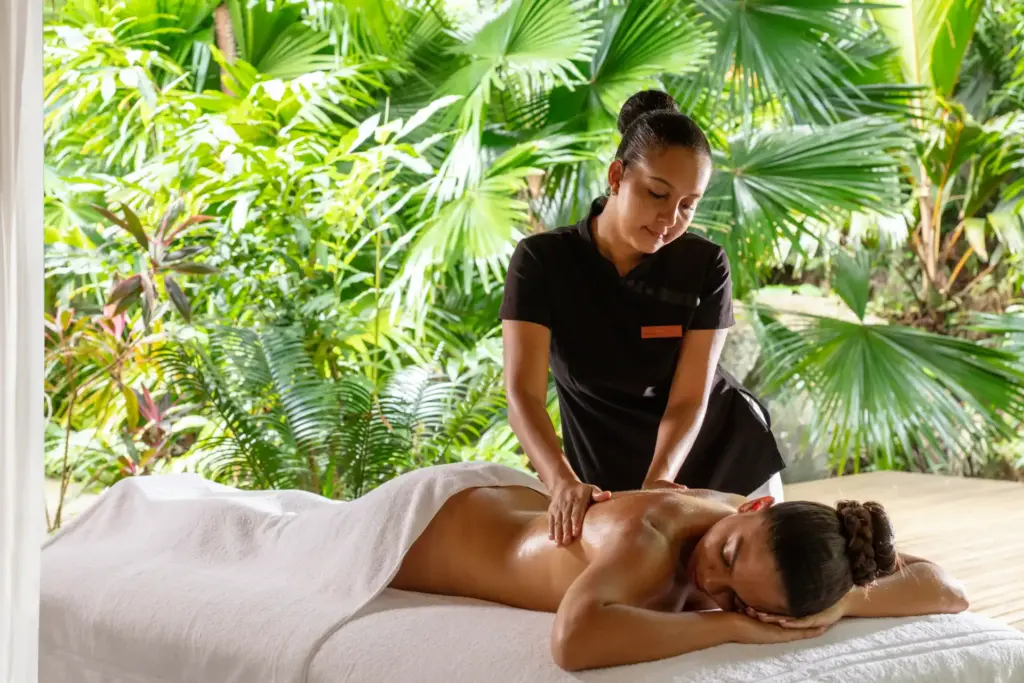 Eine Frau lässt sich vor der tropischen Kulisse der Seychellen massieren. Buchen Sie ganzheitliche Entschleunigung auf einer Trauminsel im Indischen Ozean - Seychellen-Expertin Katharina Fenners organisiert den maßgeschneiderten Aufenthalt!