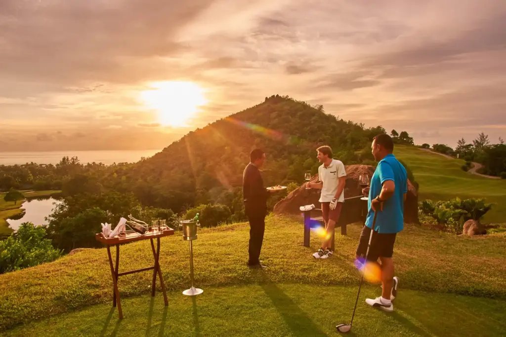 Golfspieler im Sonnenuntergang in atemberaubender Bergkulisse, im Hintergrund der Indische Ozean - die Seychellen sind ein hervorragendes Ziel für Golfliebhaber. Buchen Sie eine Seychellen Golfreise bei Golf-Expertin Katharina Fenners!
