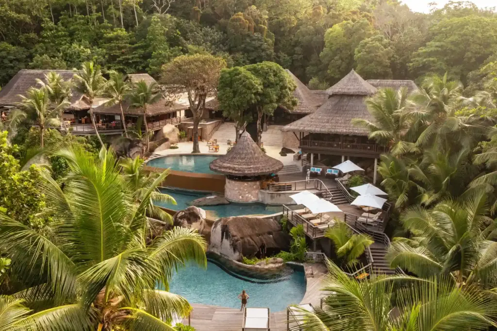 Der Hauptpool des Constance Lemuria Seychelles fügt sich auf mehreren Ebenen in die tropisch-grüne Umgebung ein. Buchen Sie einen unvergesslichen Aufenthalt in diesem Seychellen Luxusresort bei Fenners Reisen!
