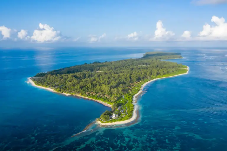 Blick aus der Luft auf die Privatinsel Desroches Island, nur eine halbe Flugstunde von Mahé entfernt. Hier liegt das Four Seasons Resort Seychelles at Desroches Island. Es ist das einzige Hotel auf der Insel und verwöhnt mit seinen intimen 5-Sterne-Luxusunterkünften.