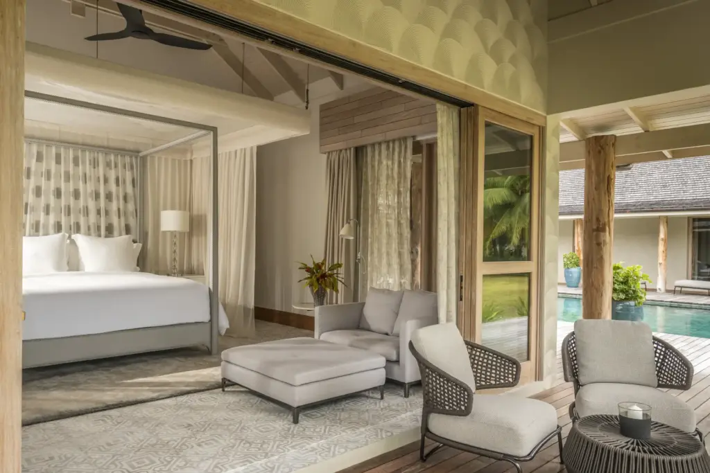 Besonders viel Platz bietet sich auf Desroches Island den Gästen der Residenzvillen - das Schlafzimmer dieser Residenz öffent sich hin zu einem gemütlichen Wohnbereich mit Blick auf einen Patio mit Pool. Buchen Sie einen exklusiven Aufenthalt auf der intimen Privatinsel Desroches Island bei Fenners Reisen!