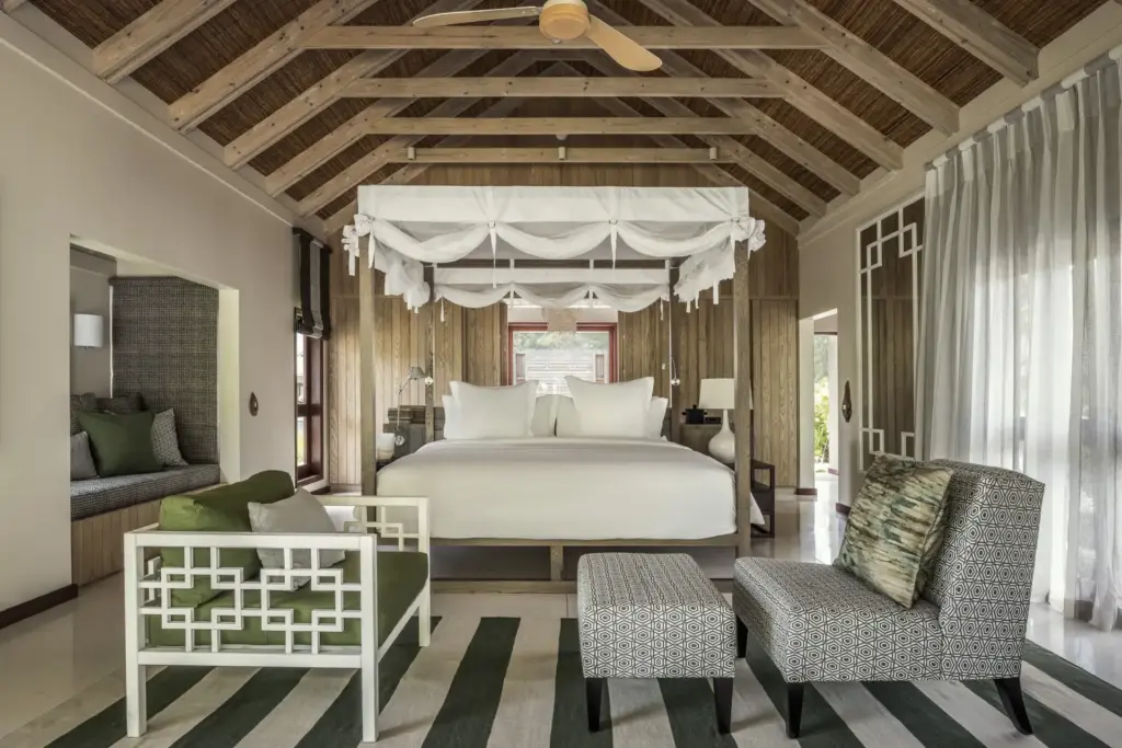 Klare Linien, natürliche Materialien und dezente Nuancen prägen dieses Schlafzimmer einer Beach Pool Villa auf den Seychellen, buchbar für Ihren Seychellen Luxusurlaub bei Fenners Reisen.