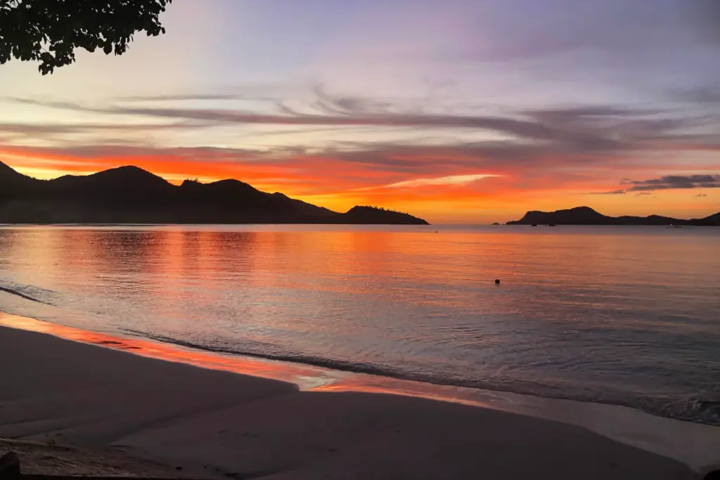 Der rot leuchtende Indische Ozean im Sonnenuntergang - ein krönender Tagesabschluss im Rahmen eines Seychellen Luxusurlaubs, buchbar bei Fenners Reisen. Lassen Sie sich gleich umfassend beraten - persönlich und individuell!