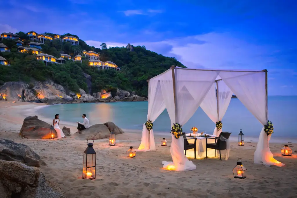Hochzeitssetting am abendlich beleuchteten Strand vor dem Banyan Tree Samui. Das ultraluxuriöse Hotel ist ein Romantiktipp für eine Hochzeit oder Hochzeitsreise in Thailand - maßgeschneidert und individuell organisiert von Fenners Reisen.