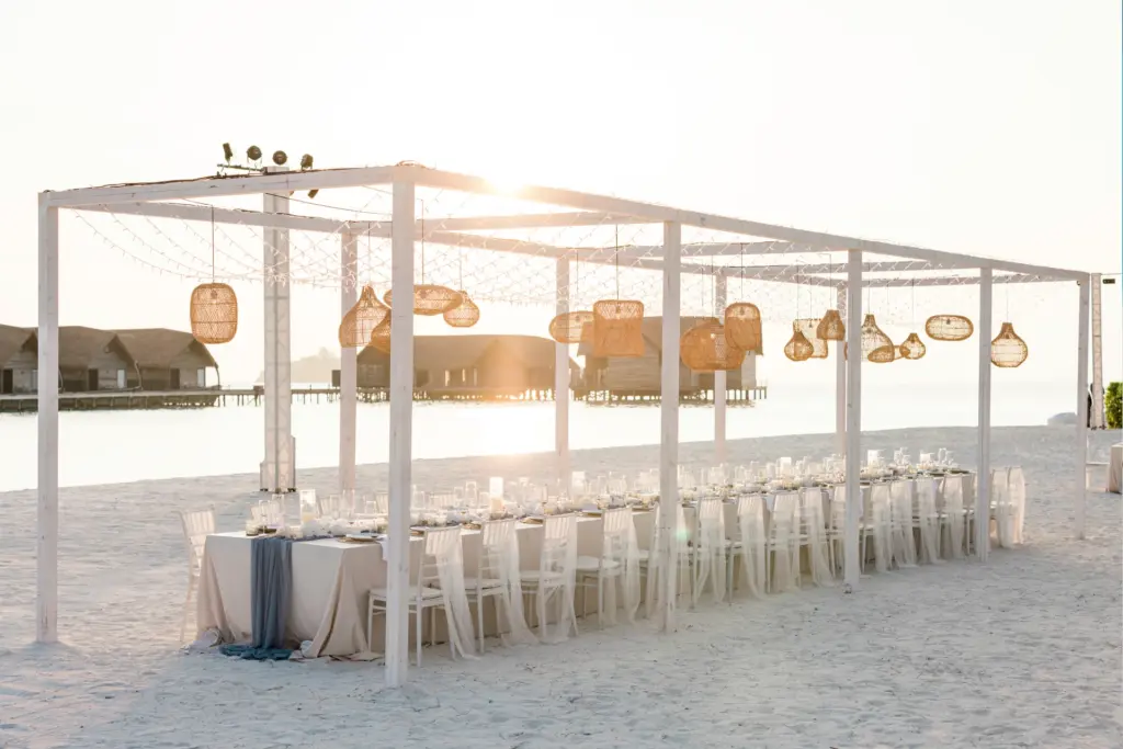 Eine festlich gedeckte Tafel für eine Hochzeitsgesellschaft am Strand einer maledivischen Insel. Planen Sie Ihre Traumhochzeit auf den Malediven bei Fenners Reisen!