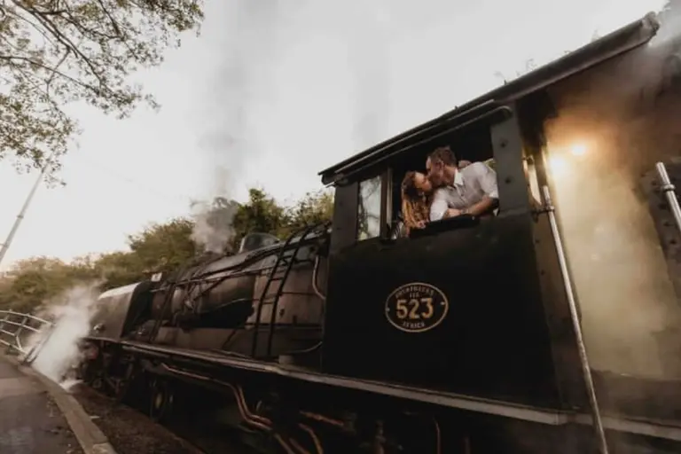 Verliebte küssen sich in einer afrikanischen Dampflok - eine Luxus-Safari im Rahmen der Hochzeitsreise kann ein echtes Once In A Lifetime Aventeuer sein! Katharina Fenners weiß, wie Ihre Hochzeitsreise wirklich unvergesslich wird!