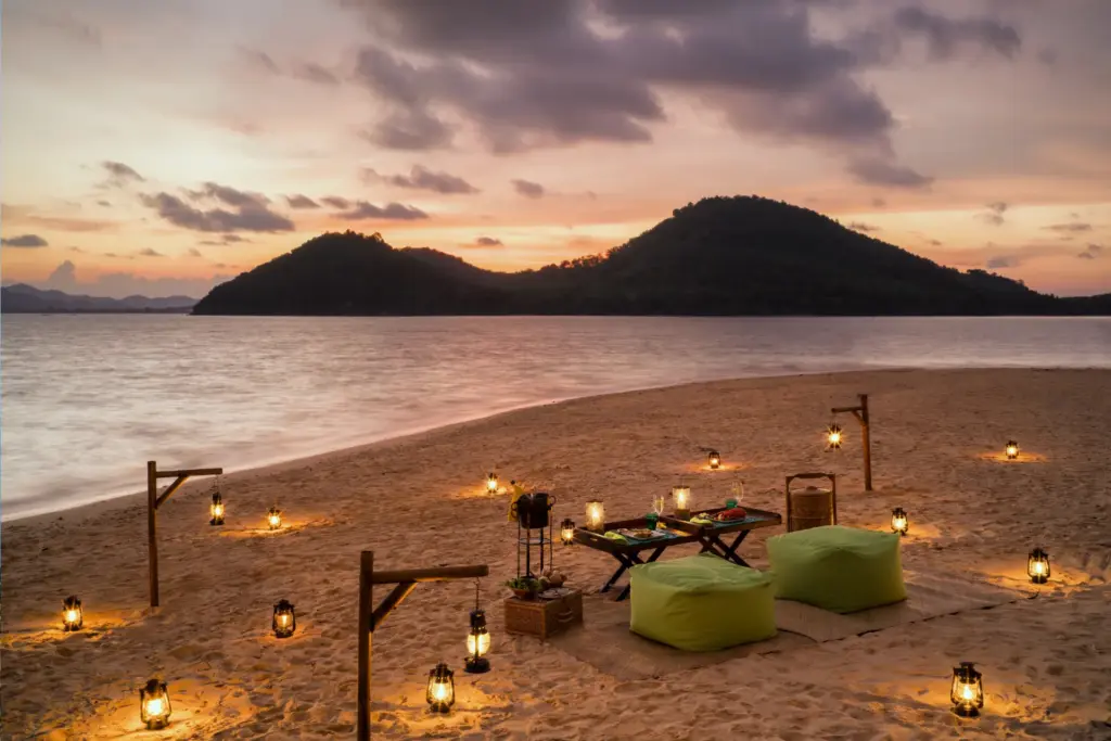 Romantisches Dinner-Set-up am thailändischen Traumstrand. Katharina Fenners verwirklicht nicht nur unvergessliche Hochzeitsreisen nach Thailand, auch Barfuß-Trauungen am Bilderbuchstrand oder Erneuerungen des Eheversprechens vor atemberaubender Naturkulisse sind möglich.