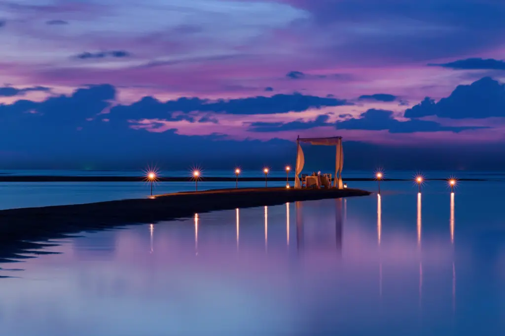 Ein festlicher Pavillon am Ende einer Sandbank in der blau-rosa Abenddämmerung - genießen Sie während Ihrer Hochzeitsreise romantische Dinner in atemberaubendem Setting und noch viel mehr. Katharina Fenners berät Sie individuell und persönlich!