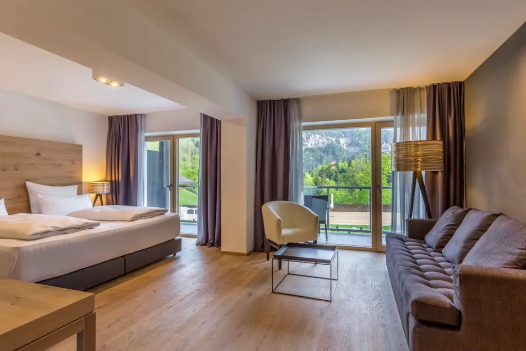 Diese Junior Suite mit Panoramablick zur Sonnenseite verfügt neben dem Kingsize-Bett auch über eine gemütliche Sitzecke mit spektakulärem Bergblick. Buchbar für Ihren Gesundheitsurlaub in Bayern bei Fenners Reisen!