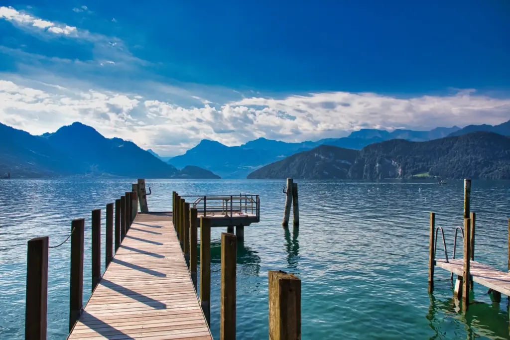 Ein Steg an einem malerischen See, im Hintergrund zeichnen sich die Umrisse imposanter Berge ab - viele Wellnessresorts liegen traumhaft inmitten schönster Natur. Katharina Fenners kennt die besten Wellnessresorts und berät Sie individuell!