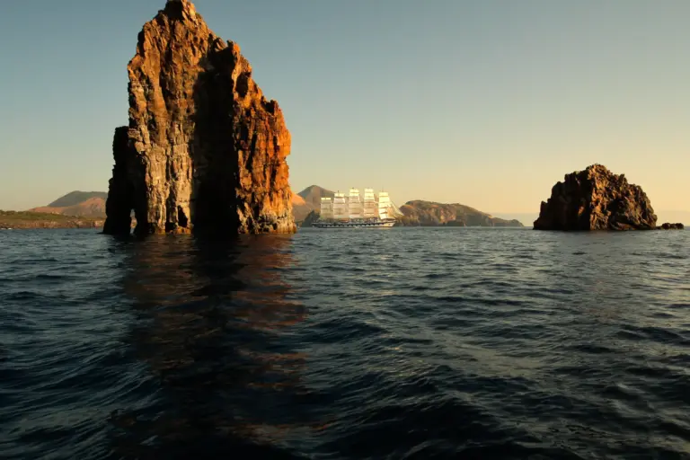 Ein mittelgroßes Segel-Kreuzfahrtschiff zwischen ikonischen Felsen - Kreuzfahrten führen zu spektakulären Zielen weltweit, ohne dass Sie Ihre Koffer ein- und auspacken müssen. Lust auf Abenteuer? Katharina Fenners organisiert Ihren individuellen Kreuzfahrturlaub!