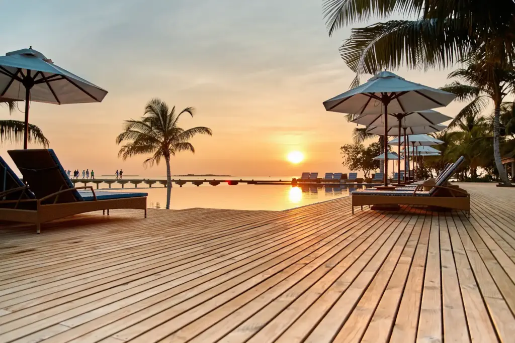 Der Hauptpool des ROBINSON Noonu im Sonnenuntergang - buchen Sie einen traumhaften Maledivenurlaub im exklusiven Clubresort bei Fenners Reisen!