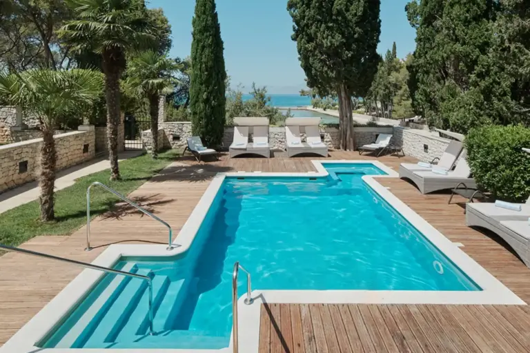 Der großzügige Pool einer Luxusvilla, umrahmt von Zypressen - mieten Sie dieses intime Feriendomizil auf der Insel Brac in Kroatien bei Fenners Reisen!