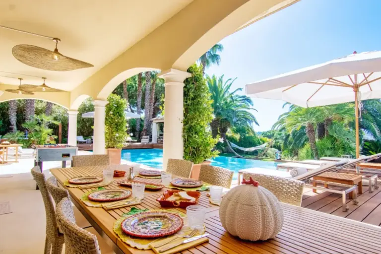 Eine festlich gedeckte Tafel auf der Terrasse eines Feriendomizils, im Hintergrund ein blauer Pool und viel Grün. Sie möchten eine Ferienvilla mieten? Katharina Fenners ist weltweit vernetzt und berät Sie individuell.