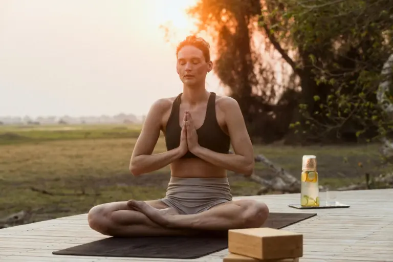 Eine Frau praktiziert Yoga auf einer Holzterrasse, im Hintergrund die afrikanische Weite. Viele außergewöhnliche Camps und Lodges bieten mehr als nur Safari. Katharina Fenners berät Sie individuell!