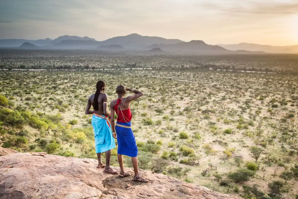 Zwei Massai-Frauen werfen einen Blick auf die weite Landschaft Kenias - im Kenia Urlaub warten kulturelle Highlights und authentische Begegnungen mit der Bevölkerung vor Ort. Fenners Reisen plant Ihren vielseitigen Kenia Safari Urlaub.