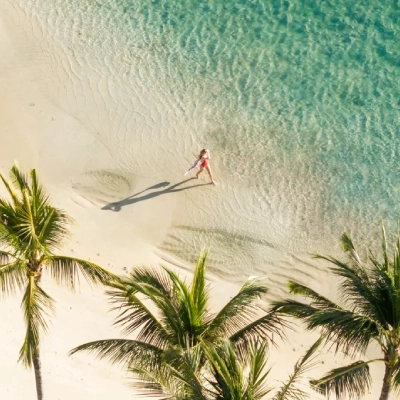 Vogelperspektive auf eine Frau, die über einen einsamen Strand auf Mauritius spaziert - Fenners Reisen ist Ihr Spezial-Reisebüro für Luxusreisen nach Mauritius und in den Indischen Ozean! Gleich individuell beraten lassen!