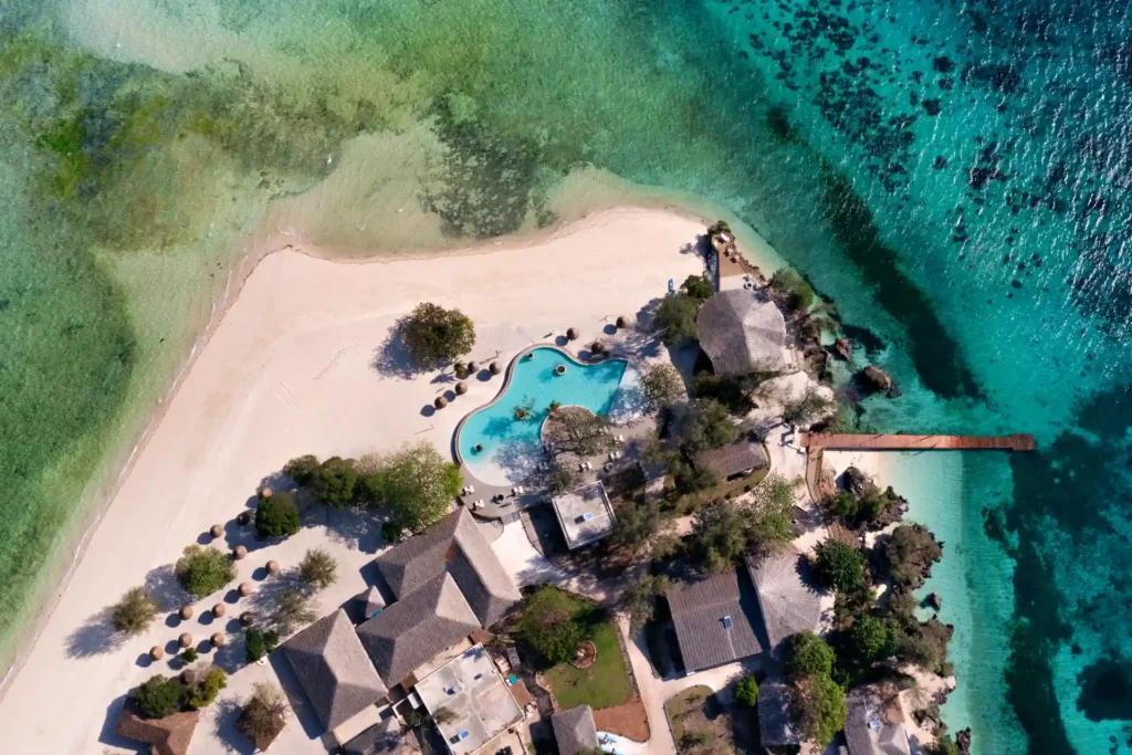 Vogelperspektive auf Villen und Pavillons mit großem Pool, umrahmt von weißem Sand und tiefblauem Meer - das ist die exklusive Privatinsel Bawe Island Zanzibar, individuell buchbar bei Fenners Reisen